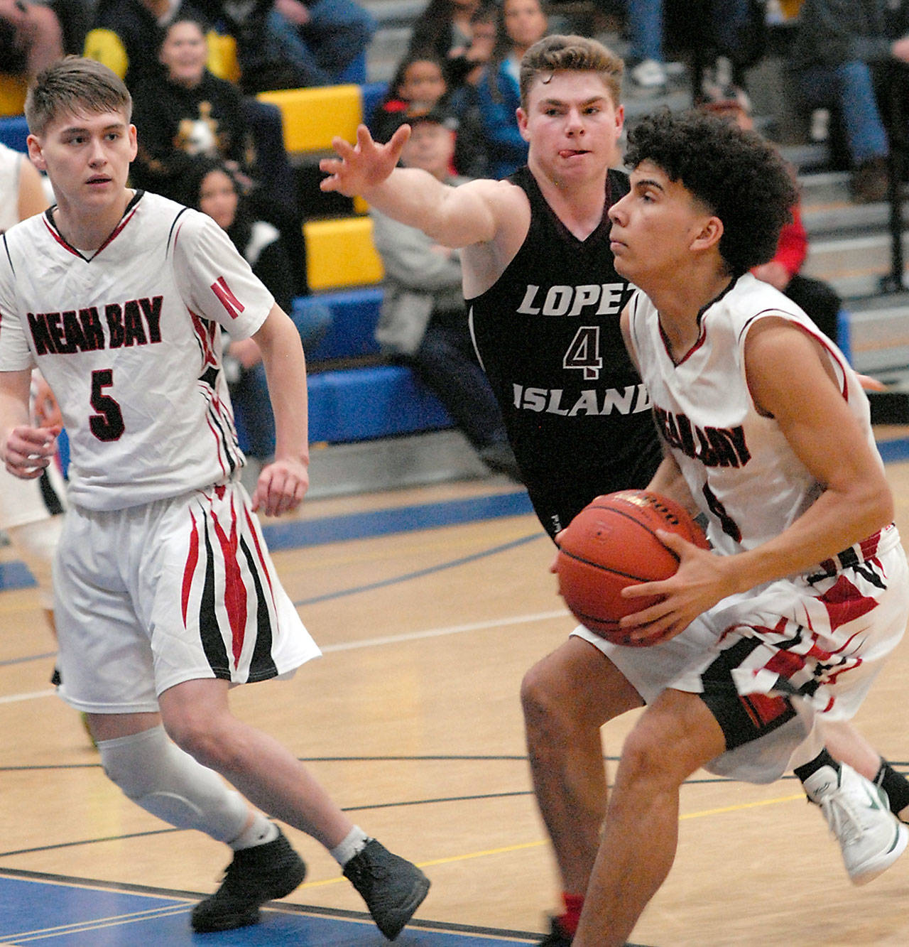 Keith Thorpe/Peninsula Daily News Neah Bay’s Jaxson Halttunen, right, heads for the lane defended by Lopez Island’s Avery Conner as Halttunen’s teammate, Darrin Horejsi looks on during Saturday’s game in Joyce.