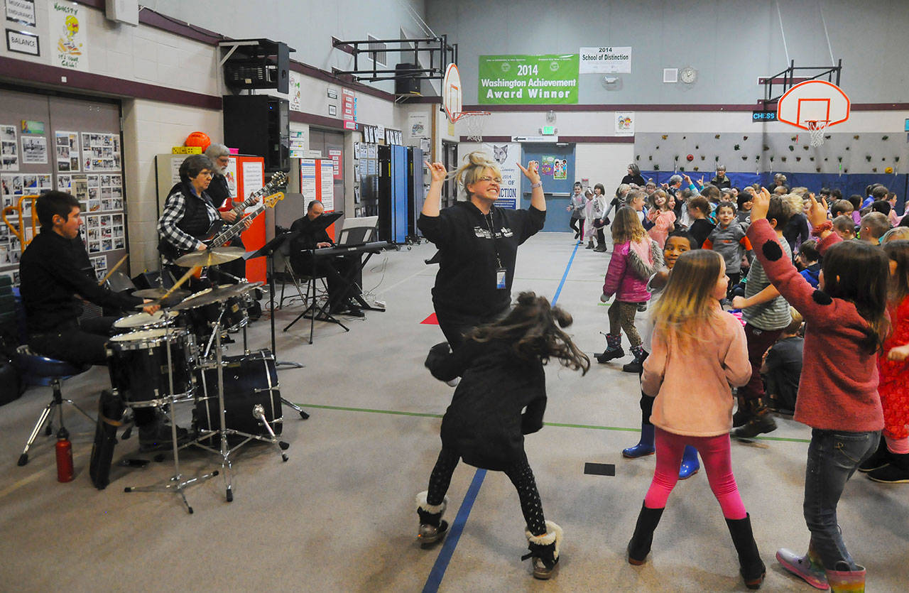 Amanda Bacon leads students in rocking out to some tunes during an Adventures In Music presentation at Greywolf Elementary School on Feb. 5. Backing Bacon are Angie Tabor (drums), Elaine Gardner-Morales (bass), Chuck Easton (guitar) and Al Harris (keyboard). Michael Dashiell/Olympic Peninsula News Group