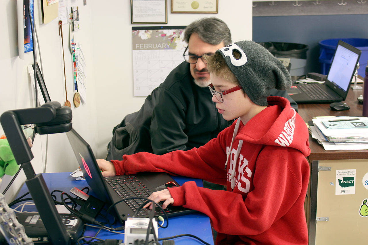 Chimacum sixth-grade student Kain Leaf, foreground, livestreams the elementary school’s Minecraft eSports Club’s meeting, in which some students were playing with others in the United Kingdom, with the assistance of teacher Al Gonzalez. (Zach Jablonski/Peninsula Daily News)