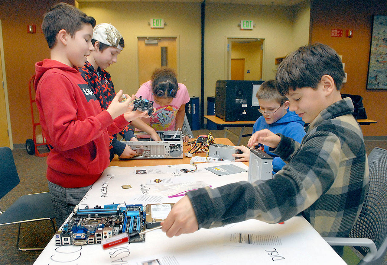 Technology enthusiasts from left, Joshua Loucks, 11, of Sequim, Max Winn, 10, of Port Angeles, Mataya Franklin, 10, of Joyce, Nicholas Morrison, 12, of Port Angeles and Malachi Byrne, 11, of Sequim tear apart a surplus computer during a teardown and deconstruction session Saturday at the Port Angeles Public Library. (Keith Thorpe/Peninsula Daily News)