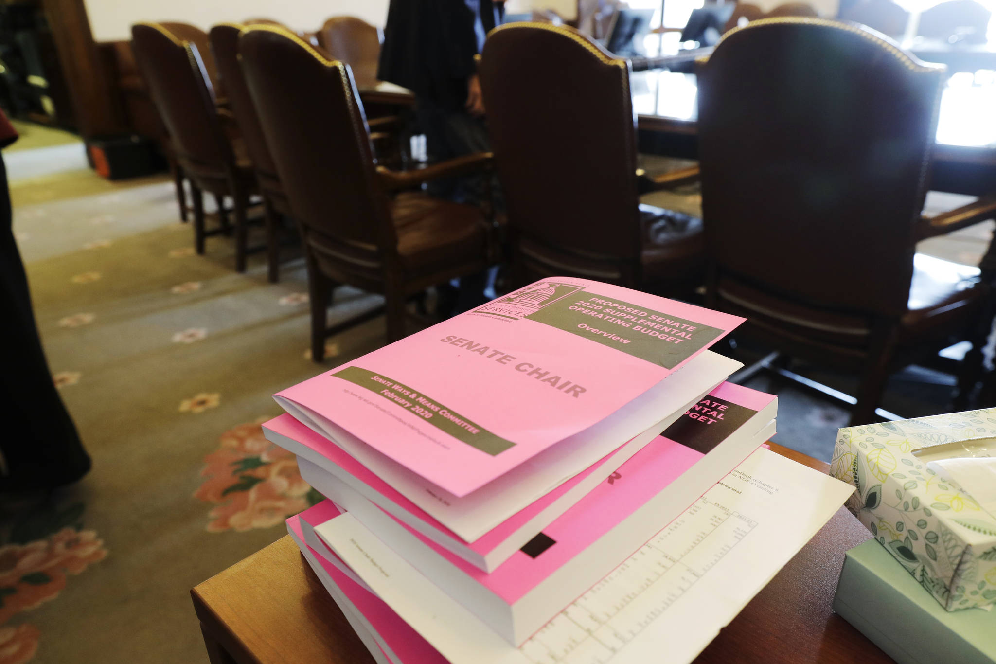 Copies of the Senate Democrats’ supplemental budget are stacked on a table Monday before a news conference at the Capitol in Olympia. (Ted S. Warren/The Associated Press)
