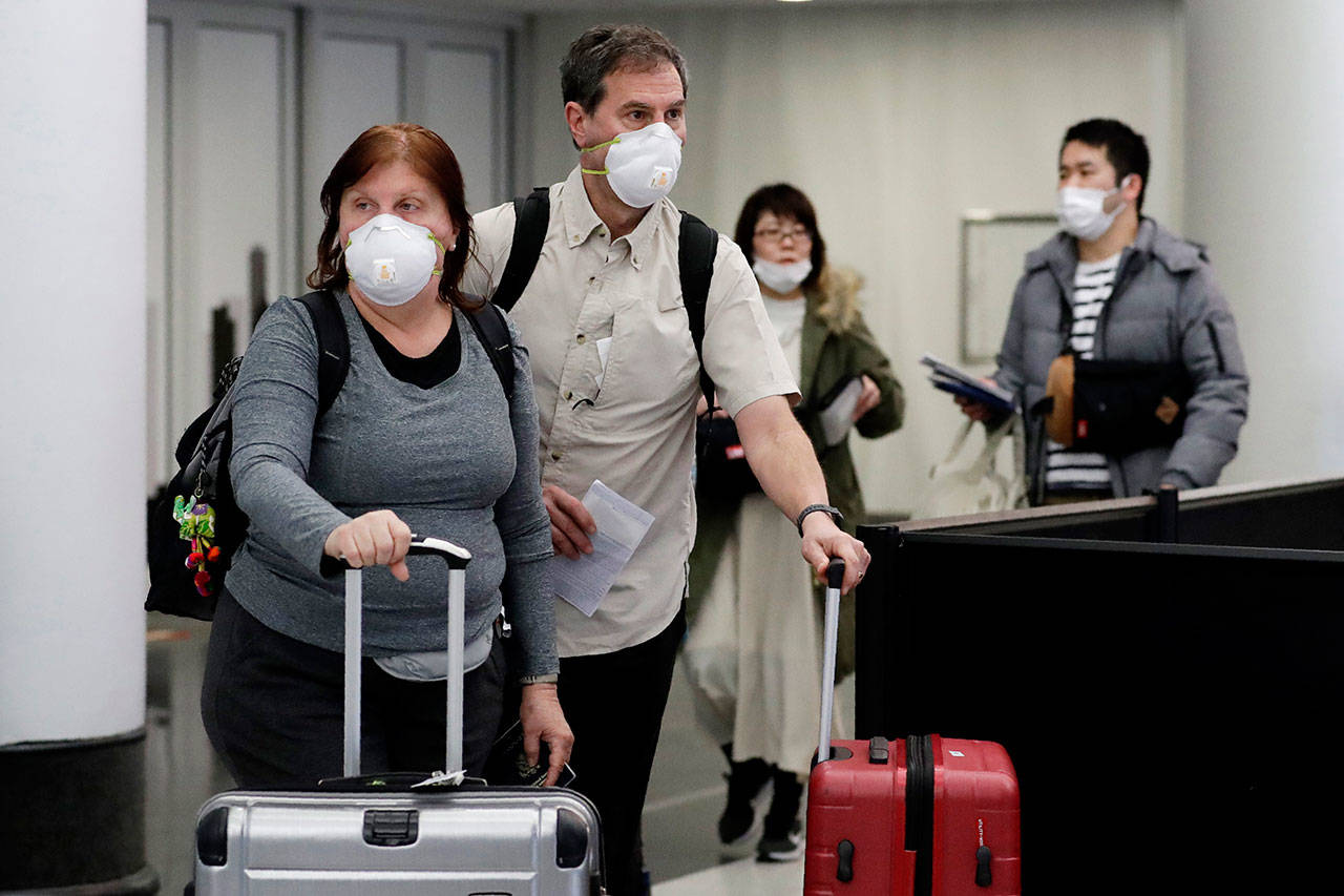 Travelers wear protective mask as they walk through in terminal 5 at O’Hare International Airport in Chicago on Sunday. (Nam Y. Huh/The Associated Press)