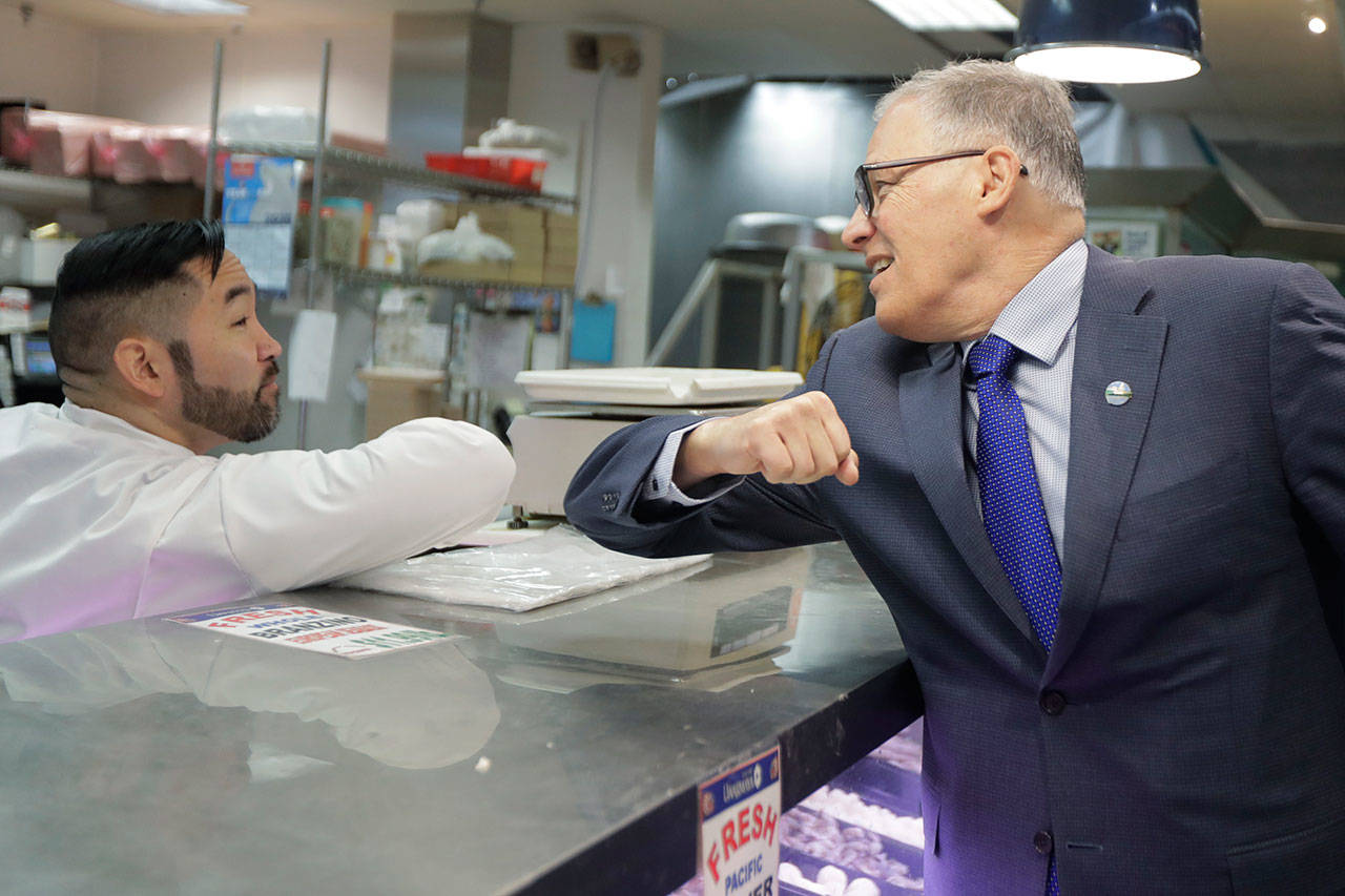 Washington Gov. Jay Inslee, right, bumps elbows with a worker at the seafood counter of the Uwajimaya Asian Food and Gift Market on Tuesday, March 3, 2020, in Seattle’s International District. Inslee said he’s doing the elbow bump with people instead of shaking hands to prevent the spread of germs, and that his visit to the store was to encourage people to keep patronizing businesses during the COVID-19 Coronavirus outbreak. (Ted S. Warren/The Associated Press)