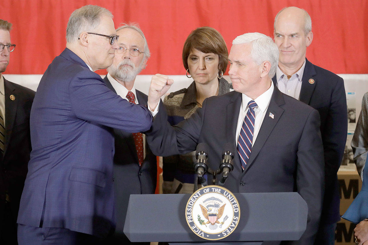 Vice President Mike Pence bumps elbows with Gov. Jay Inslee, left, during a news conference Thursday at Camp Murray in Washington state. Pence was in Washington to discuss the state’s efforts to fight the spread of the COVID-19 coronavirus, and officials have been avoiding shaking hands to prevent the spread of germs. (Ted S. Warren/The Associated Press)