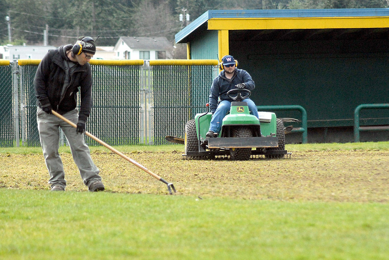 Port Angeles Parks and Recreation Department employee Lukas Cox, right, uses a lawn tractor to condition the baseball infield at Volunteer field on Thursday as coworker Eli Hammel edges along the outfield grass. Prep sports practices continued at North Olympic Peninsula high schools on Thursday. (Keith Thorpe/Peninsula Daily News)