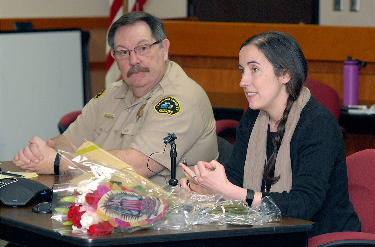 Dr. Allison Berry Unthank, Clallam County public health officer, right, discusses the novel coronavirus as Clalam County Undersheriff Ron Cameron listens in during a briefing Friday at the Clallam County Courthouse. On the desk is a bouquet of flowers presented to Unthank by County Commissioners for her efforts at keeping the public informed during the global virus pandemic. (Keith Thorpe/Peninsula Daily News)