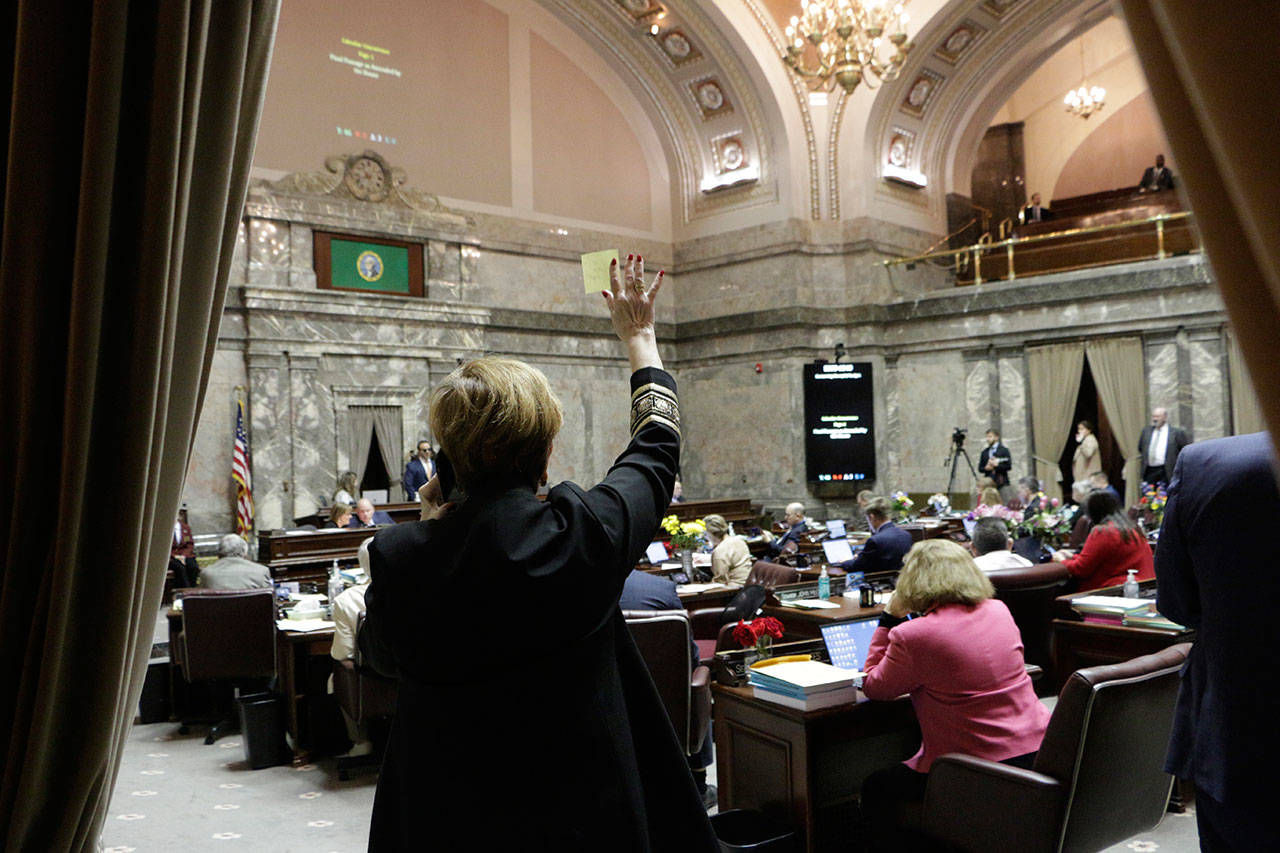 Democratic Sen. Lisa Wellman raises her hand during a vote in the state Senate on Thursday in Olympia. Lawmakers were finishing up their work amid concerns of the state’s COVID-19 outbreak. (Rachel La Corte/The Associated Press)