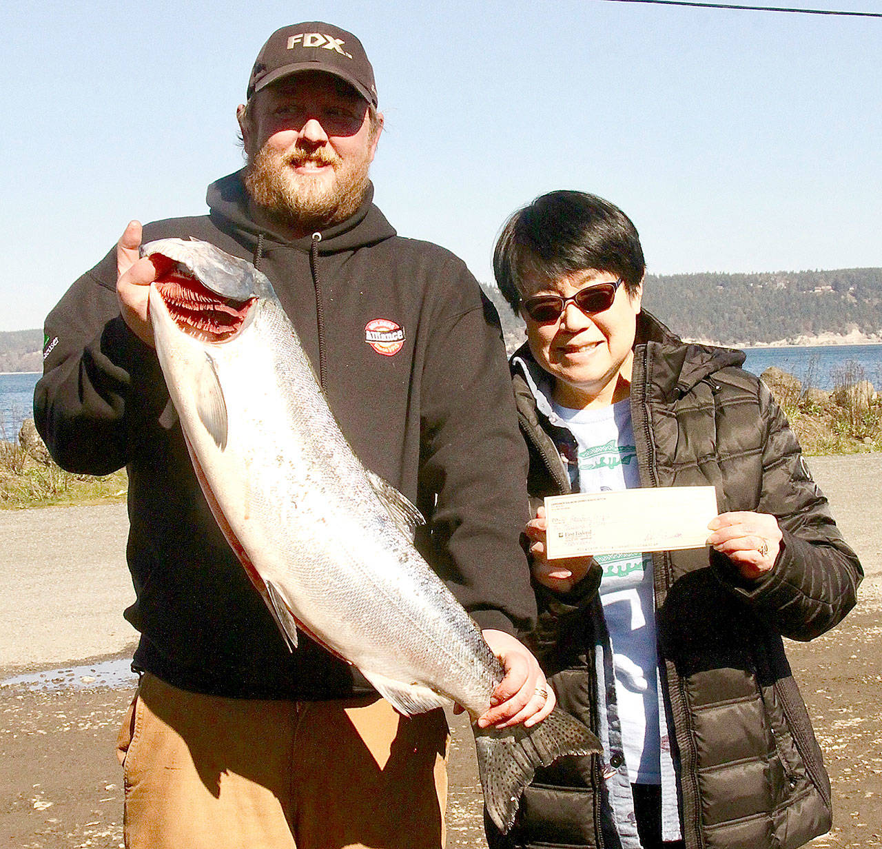 Olympic Peninsula Salmon Derby winner Brandon Leeper, left, holds his 15.7-pound catch with Kathy Watrous, Gardiner Salmon Derby Association president. (Dave Logan/for Peninsula Daily News)