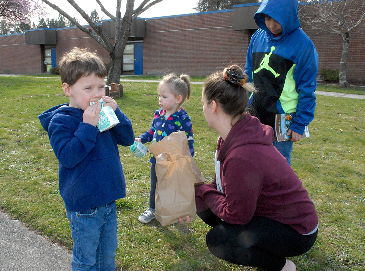 Hayden Helfer, 4, left, opens a milk carton as his sister, Ashlyn Helfer, 2, brother, Azriel Castillo, 11, and mother, Kristen Rutherford of Port Angeles, visit Hamilton School in Port Angeles for free meal for children Tuesday. (Keith Thorpe/Peninsula Daily News)
