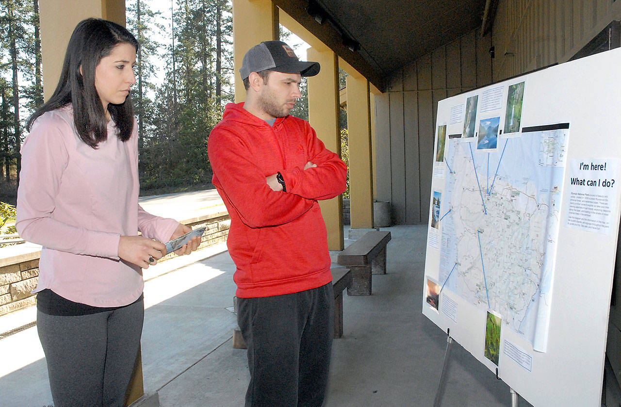 Pamela and Jacob Wilson of Oklahoma City, Okla., examine a map of Olympic National Park outside the shuttered park visitor center in Port Angeles on Wednesday. In a move to prevent the spread of the novel coronavirus, park officials decided to close three visitor centers and close Hurricane Ridge Road. However, Olympic National Park remains open to visitation and camping at several seasonal campgrounds. (Keith Thorpe/Peninsula Daily News)