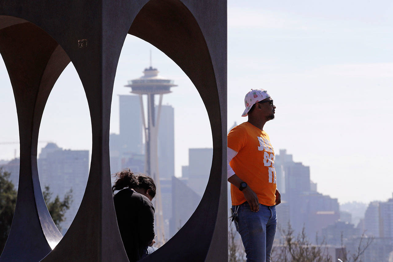 Issa Barry looks out over the Seattle skyline, including the iconic Space Needle, as he stands near a sculpture at a popular park Friday. People in the state are being asked to maintain physical distance from others to help stop the spread of COVID-19. (AP Photo/Elaine Thompson)