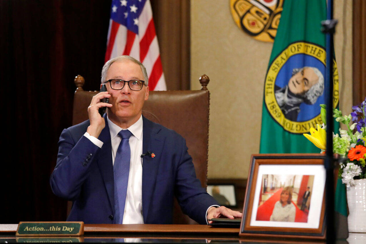 Gov. Jay Inslee takes a phone call just before speaking about additional plans to slow the spread of coronavirus before a televised address from his office Monday, March 23, 2020, in Olympia. Inslee has ordered non-essential businesses to close and the state’s more than 7 million residents to stay home unless necessary in order to slow the spread of COVID-19. (Elaine Thompson/The Associated Press)