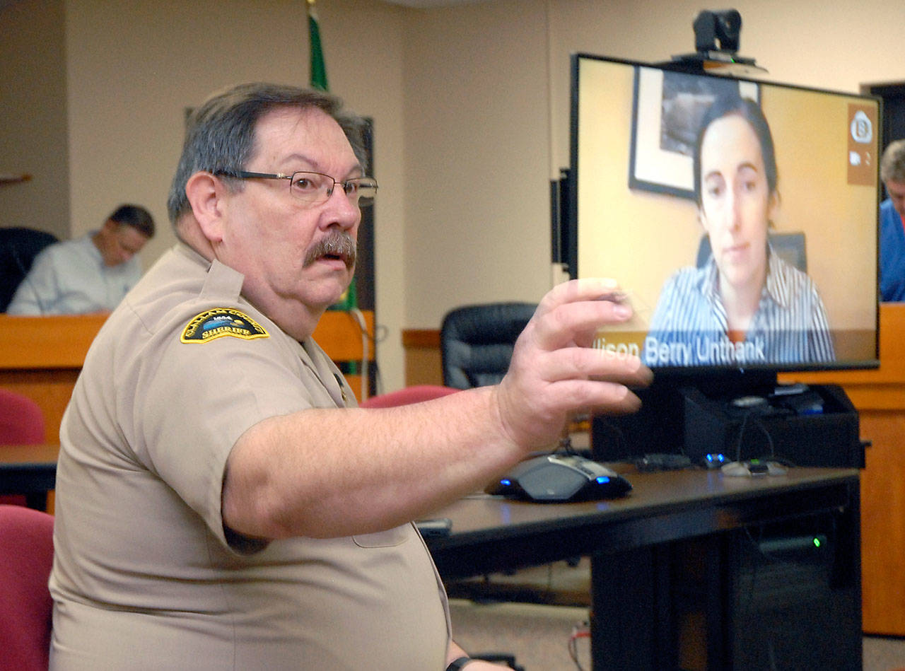 Clallam County Undersheriff Ron Cameron, left, fields questions as Dr. Allison Berry Unthank, the county’s public health officer, delivers COVID-19 updates through a video link from her home on Wednesday morning at the Clallam County Courthouse in Port Angeles. (Keith Thorpe/Peninsula Daily News)