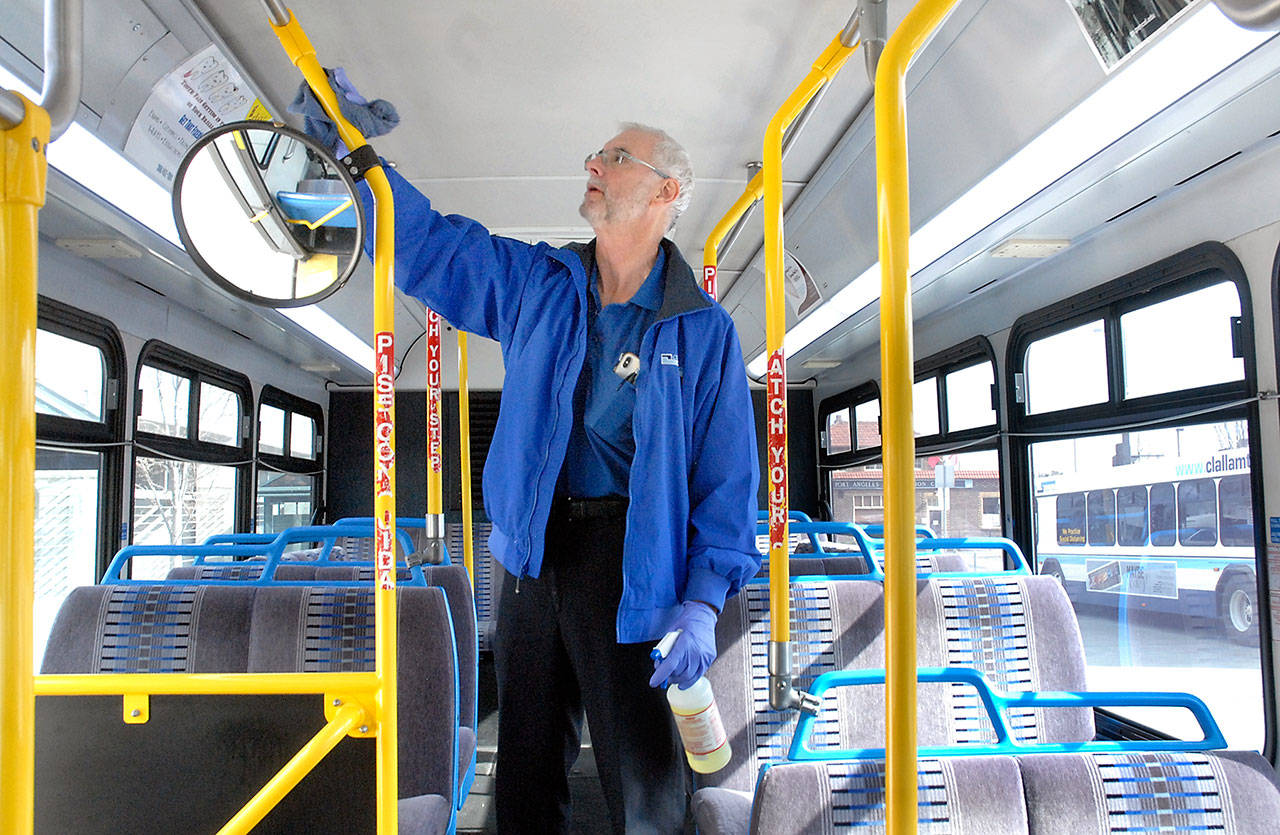 Clallam Transit driver Pete Sekac wipes down surfaces on a transit bus between runs on Thursday at The Gateway transit center in Port Angeles. The transit service has suspended fares due to the COVID-19 emergency and asking riders to enter from the back door of the bus whenever possible, and then to practice social distancing while aboard. (Keith Thorpe/Peninsula Daily News)