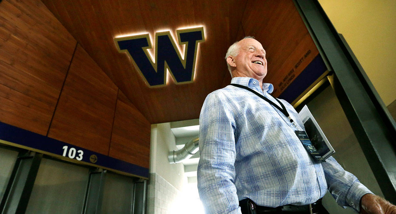 In this Aug. 28, 2013, file photo, former head coach Jim Lambright smiles as he stands at a concourse entrance in the newly renovated Husky Stadium in Seattle. Lambright died at age 77, the school announced Sunday, March 29, 2020. Lambright spent nearly four decades associated with the Washington program as a player, assistant coach and head coach. (Elaine Thompson/Associated Press file)