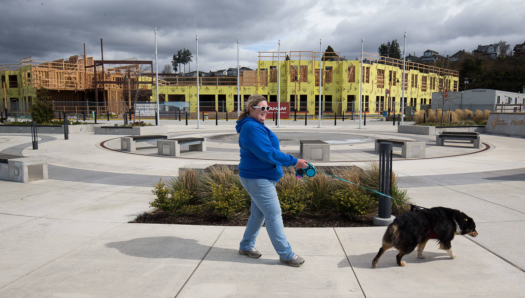 Amy Ulrich walks her dog, Kahlua, by the Waterfront Place Apartments at the Port of Everett on Monday. Gov. Jay Inslee ordered most construction projects around the state to shut down for two weeks. That paused work at several big housing projects, including this one at the port. (Andy Bronson/The Herald)