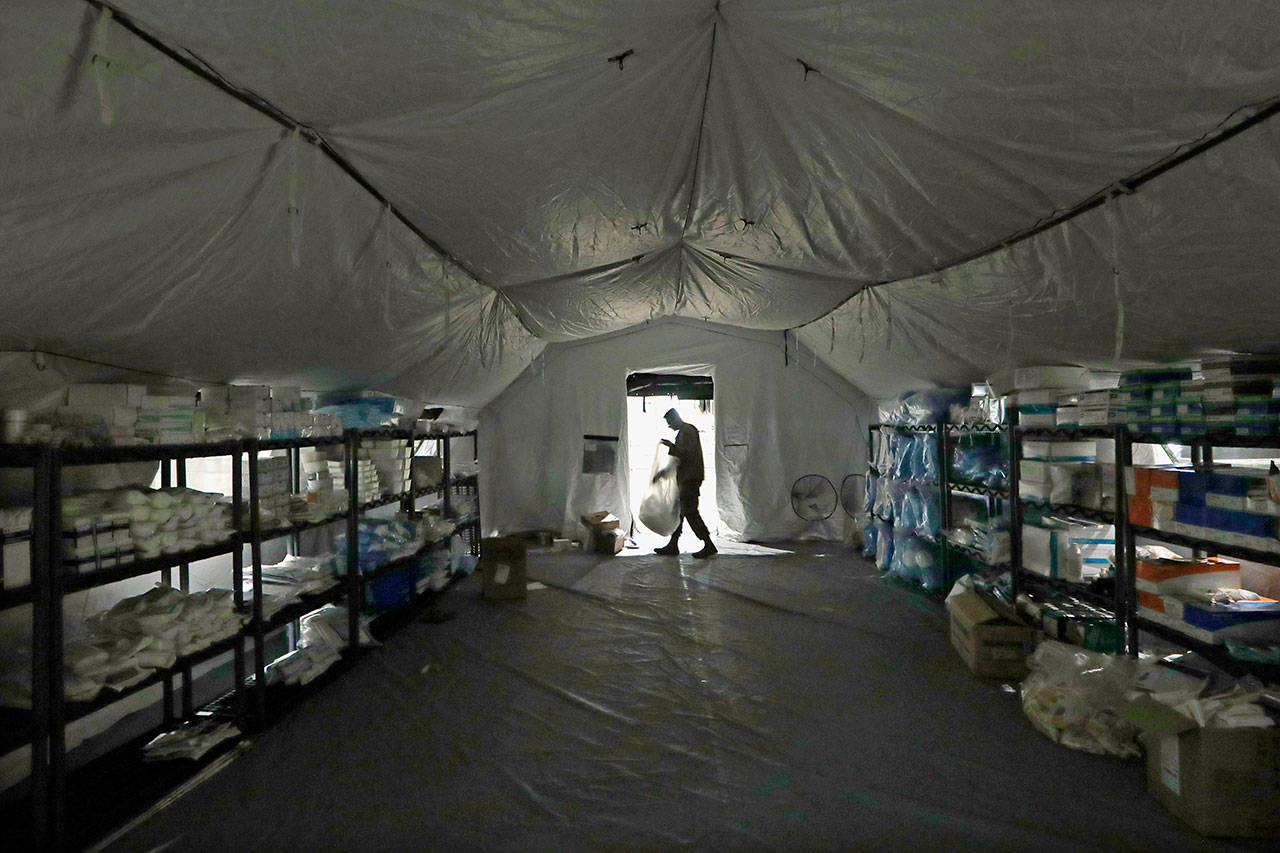 A U.S. Army soldier walks inside a mobile surgical unit being set up by soldiers from Fort Carson, Col., and Joint Base Lewis-McChord (JBLM) as part of a field hospital inside CenturyLink Field Event Center on Tuesday, March 31, 2020, in Seattle. Soldiers from the 627th Army Hospital at Fort Carson, will join soldiers from JBLM to staff the 250-bed hospital to be used for non-COVID-19 cases, allowing local hospitals additional space for patients affected by the coronavirus outbreak. Officials said that the field hospital is expected to be ready to receive patients next week. (Elaine Thompson/The Associated Press)