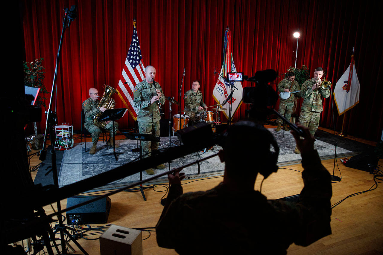 U.S. Army Field Band members from left, Chief Warrant Officer 2 Kevin Pick, on the tuba, Master Sgt. Bradford Danho, on the clarinet, Staff Sgt. Andrew Emerich, on the drums, Sgt. 1st Class Jonathan Epley, on the banjo and Staff Sgt. Kyle Johnson, on the trombone, are spaced to allow for social distancing as they play during the rehearsal of their daily “We Stand Ready” virtual concert series at Fort George G. Meade in Fort Meade, Md., on Wednesday, March 25, 2020. The Army Field Band’s mission is to bring the military’s story to the American people. And they’re not letting the coronavirus get in the way. (Carolyn Kaster/The Associated Press)