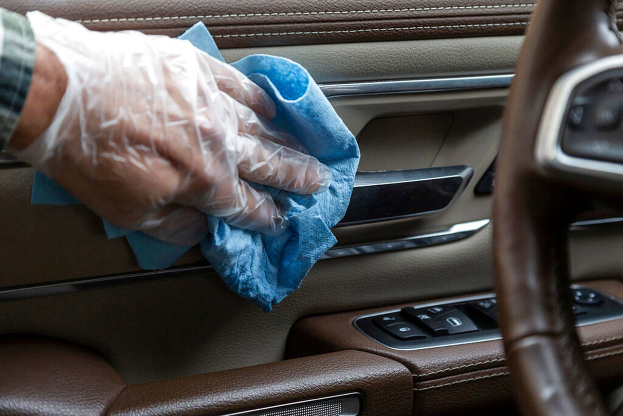 In this undated photo from Edmunds, common touch points are wiped down in the interior of a vehicle, which is one way to reduce the risk of spreading the coronavirus inside the cabin. Apply disinfectant using wipes or spray disinfectant onto a soft cloth, and use disposable gloves to protect your hands. (Scott Jacobs/Edmunds via AP)