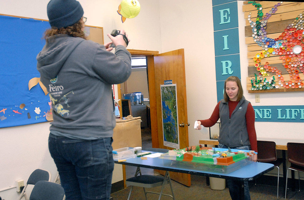 Feiro Marine Life Center Education Manager Rachele Brown, right, gives a presentation about water pollution in an urban setting as Facilities Director Tamara Galvin records it on video as part of an educational program for fourth-grade students kept from their classrooms by the COVID-19 health emergency. (Keith Thorpe/Peninsula Daily News)