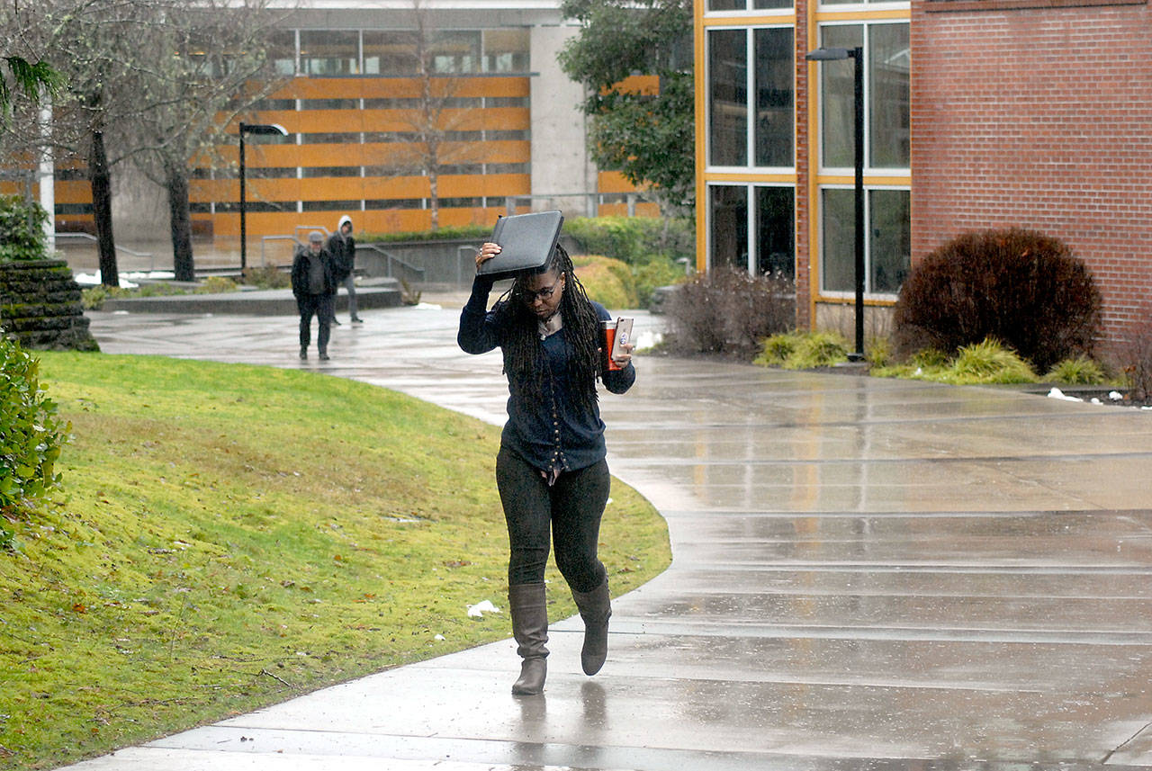 Nitasha Lewis, a manager with the Upward Bound program at Peninsula College, uses a paper valise to keep her head dry as she walks across the college’s Port Angeles campus Feb. 6, 2020. The college is going to online classes for the entirety of the 2020 spring quarter. (Keith Thorpe/Peninsula Daily News file)