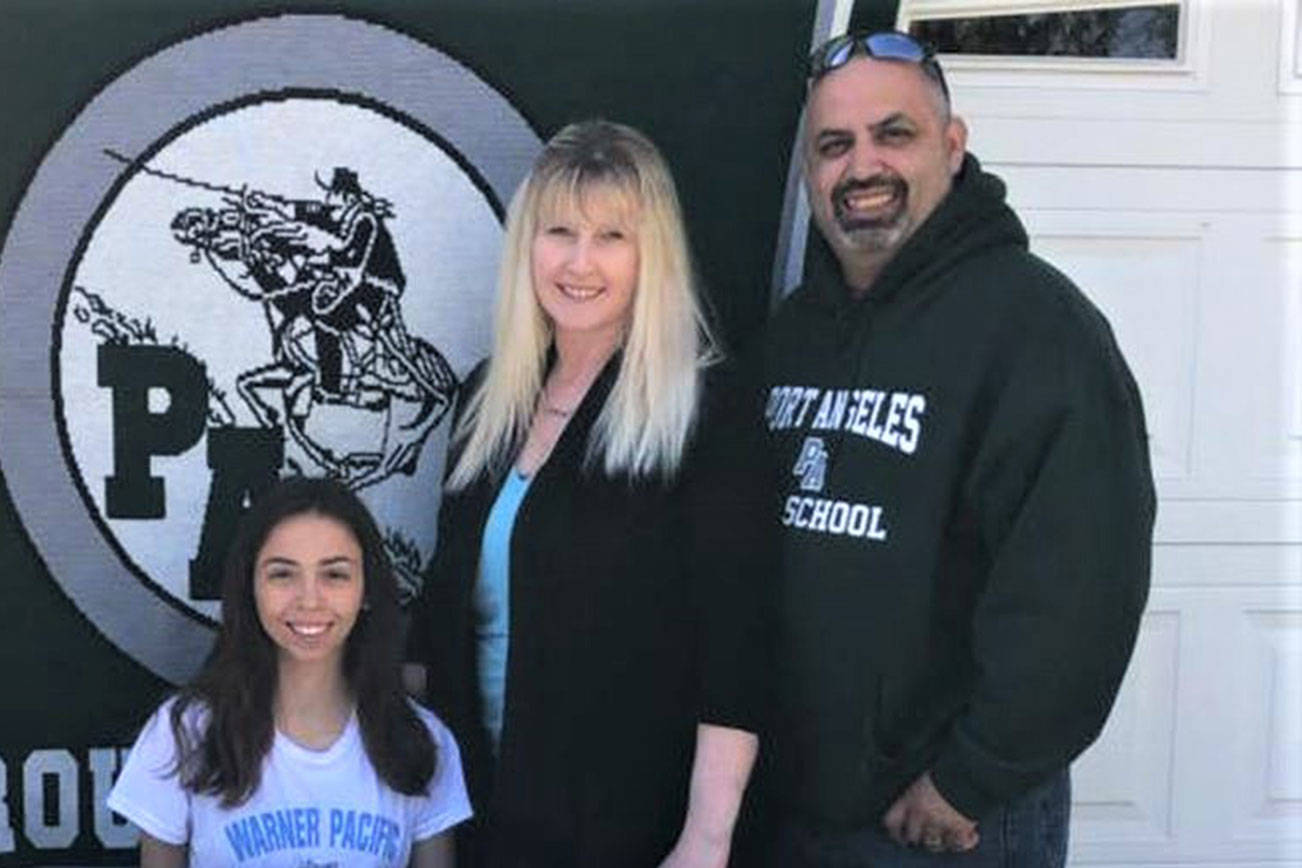 Port Angeles Roughrider Kynzie DeLeon, left, signs her letter of intent to run track and field and cross country at Warner Pacific University in Portland, Ore., along with her parents, Tamie and Dan DeLeon, at right.
