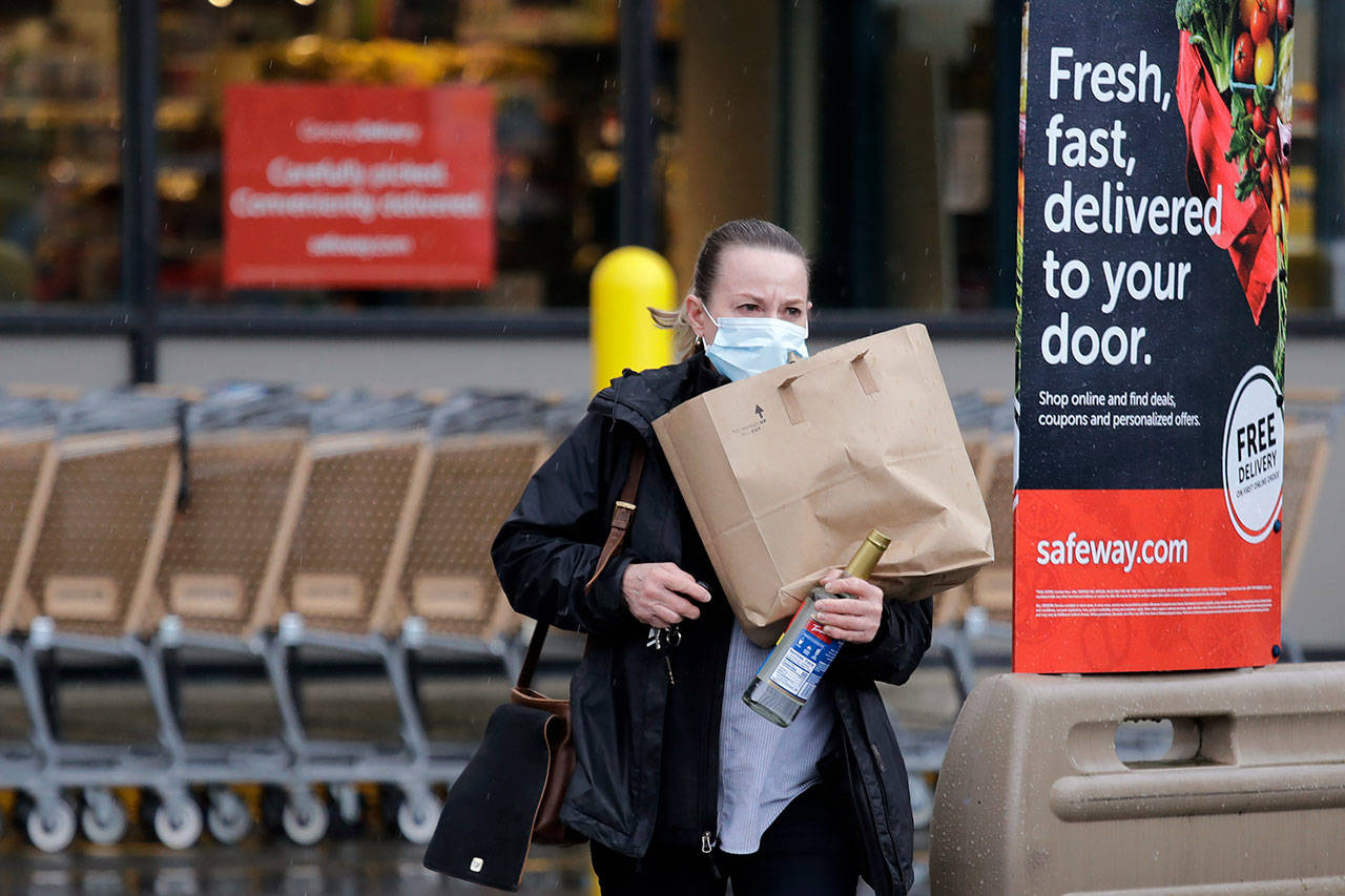 In this Monday, March 30, 2020, photo, a shopper leaves a grocery store with food packed in a paper bag in Seattle, where the dime-per-bag fee has been waved during the coronavirus outbreak. (Elaine Thompson/The Associated Press)