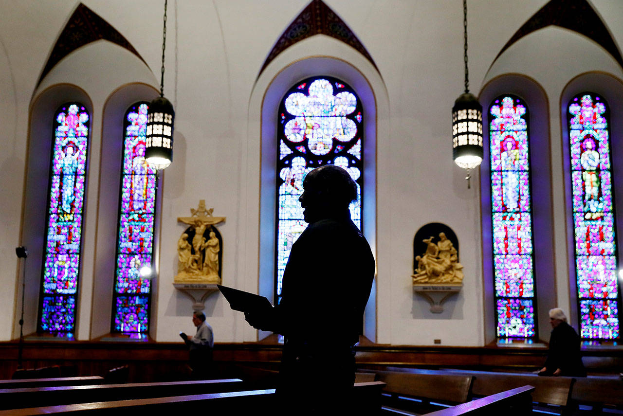 A church member prays during a Good Friday service at St. Ambrose Cathedral on Friday, April 10, 2020, in Des Moines, Iowa. COVID-19 causes mild or moderate symptoms for most people, but for some, especially older adults and people with existing health problems, it can cause more severe illness or death. (Charlie Neibergall/The Associated Press)