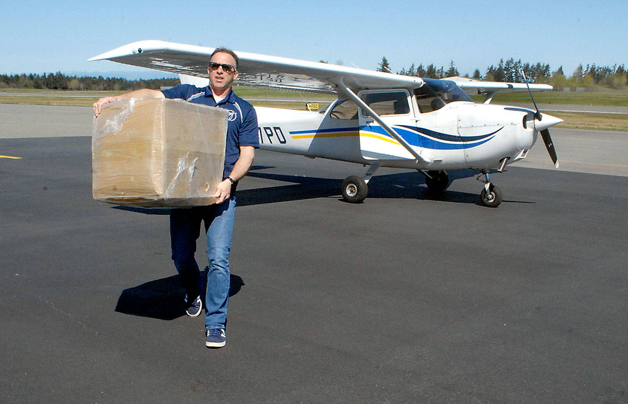 Kevin Chaney of Seattle, a member of the Boeing Employees’ Flying Association, offloads one of four boxes containing a total of 30,000 surgical masks destined for Olympic Medical Center after two aircraft arrived at William R. Fairchild International Airport in Port Angeles on Thursday, April 16, 2020, with supplies from the Washington State Hospital Association. (Keith Thorpe/Peninsula Daily News)
