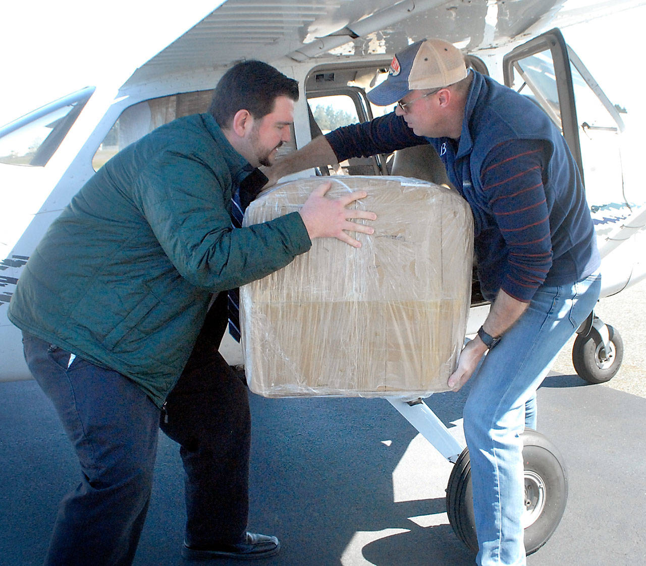 Bastian Hardtke, purchasing manager at Olympic Medical Center, left, takes a box from Boeing Employee’s Flying Association member Doug Weller of Seattle after two aircraft containing 30,000 surgical masks for the hospital arrived on Thursday at William R. Fairchild International Airport in Port Angeles on Thursday, April 16, 2020. (Keith Thorpe/Peninsula Daily News)