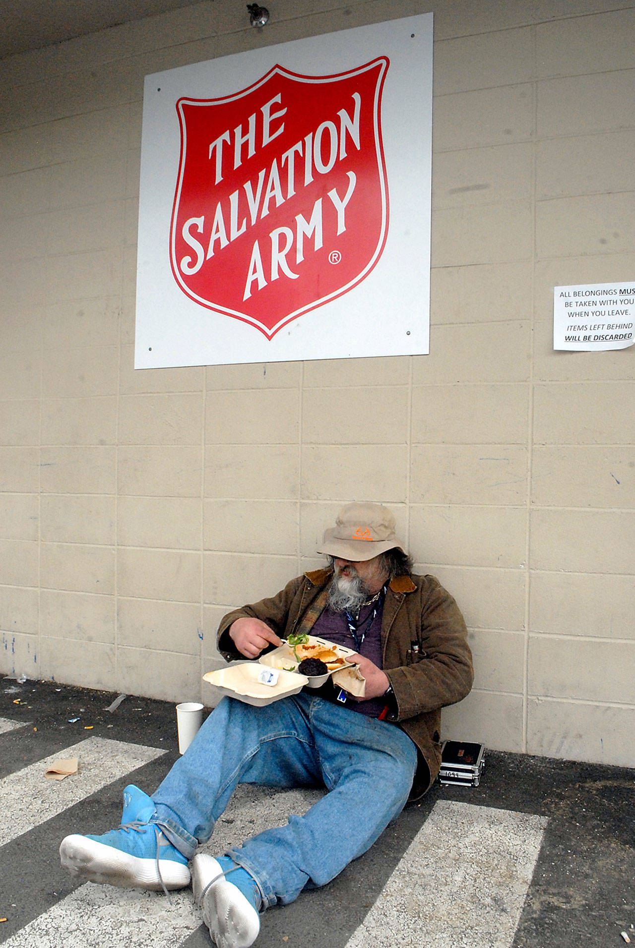 Brian, who declined to give a last name, sits in the Salvation Army parking lot after receiving a carry-out lunch on Friday at the organization’s Port Angeles kitchen. (Keith Thorpe/Peninsula Daily News)