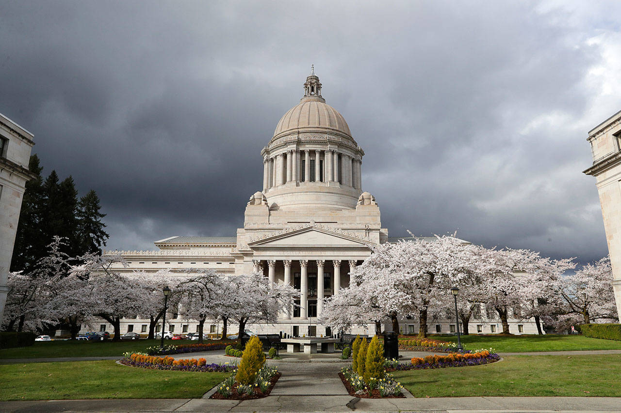 In this photo taken March 23, 2020, cherry trees bloom next to the Capitol building in Olympia, Wash. Even once Washington’s economy fully reopens following the coronavirus outbreak, the effect on state revenues is expected to be felt for months and maybe years to come, leading state officials to start preparing for inevitable budget cuts now. (AP Photo/Elaine Thompson)