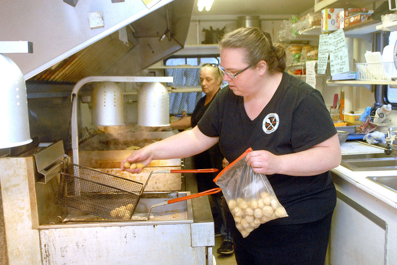Corner Caboose co-owner Shannon Reynolds, front, loads tater tots into a fryer as cook Janine Romero tends the grill during Friday’s lunch rush. (Keith Thorpe/Peninsula Daily News)