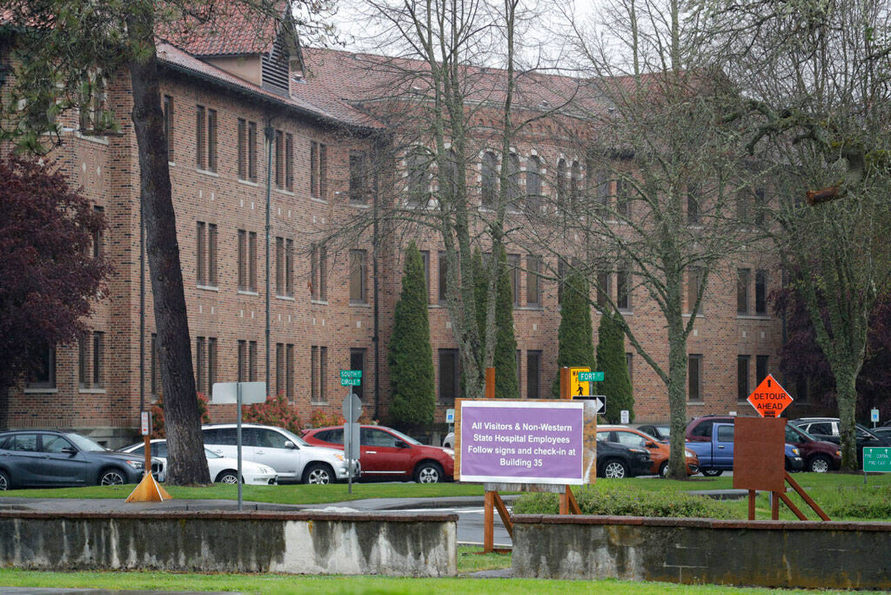 In this April 22, 2020, photo, a sign at Western State Hospital in Lakewood, Wash., directs visitors and non-hospital employees to check in at another building where health screening is done. Employees at the facility — the state’s largest psychiatric hospital — say that problems with testing for the coronavirus likely produced inaccurate results and exposed them to the virus a second time. (Ted S. Warren/Associated Press)