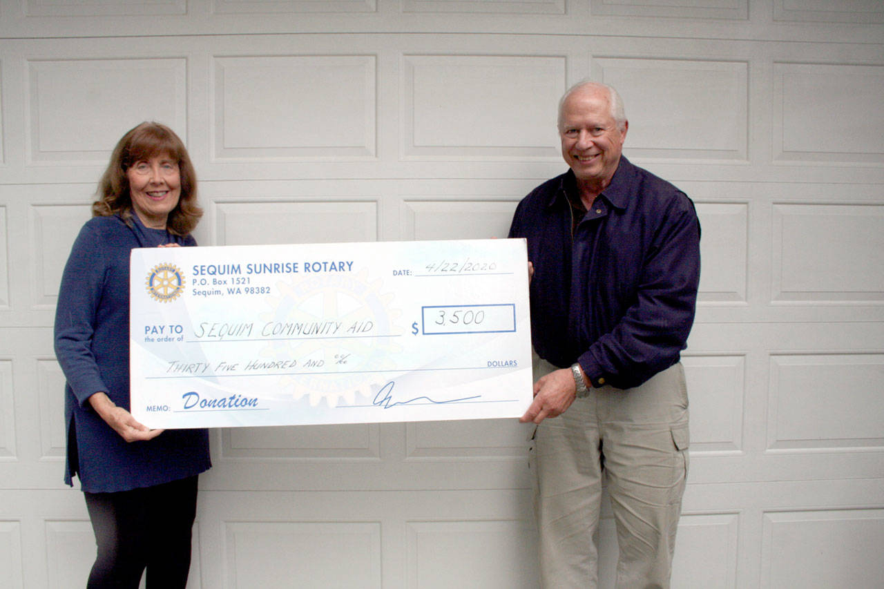 Kathy Suta, president of Sequim Community Aid, accepts a $3,500 donation from Russ Mellon, president of Sequim Sunrise Rotary. (Submitted photo)