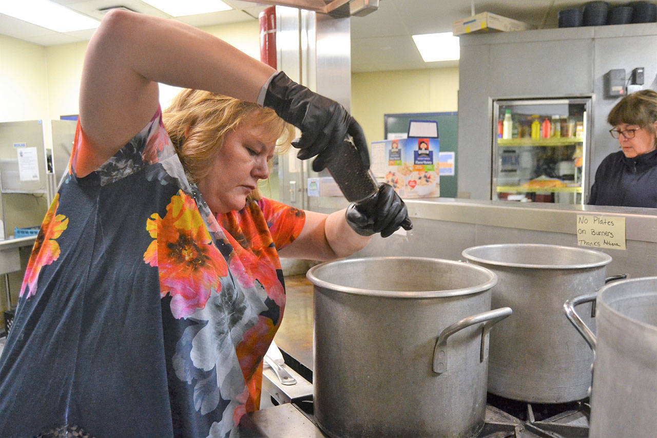 Shelley Jefferson, the assistant principal at Helen Haller Elementary in Sequim, adds seasoning to a soup. The program provides soup four nights a week to four different apartment complexes. (Matthew Nash /Olympic Peninsula News Group