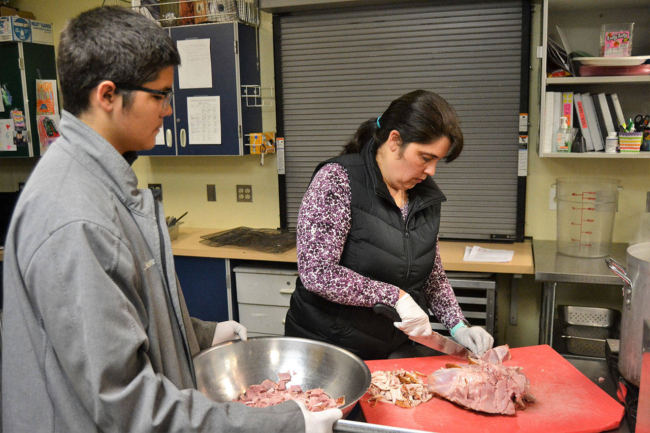Andy Beniutez and his mom, Anita Benitez, prep ham for split pea and ham soup during a recent night of soup prep. Anita is one of many Sequim School District staffers volunteering with the program. (Matthew Nash/Olympic Peninsula News Group)