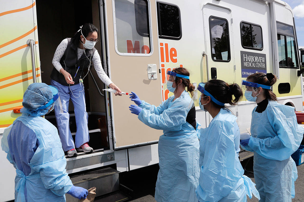 Medical assistants wait to be handed testing kits at a drive-up coronavirus testing site Wednesday, April 29, 2020, in Seattle. (Elaine Thompson/Associated Press)