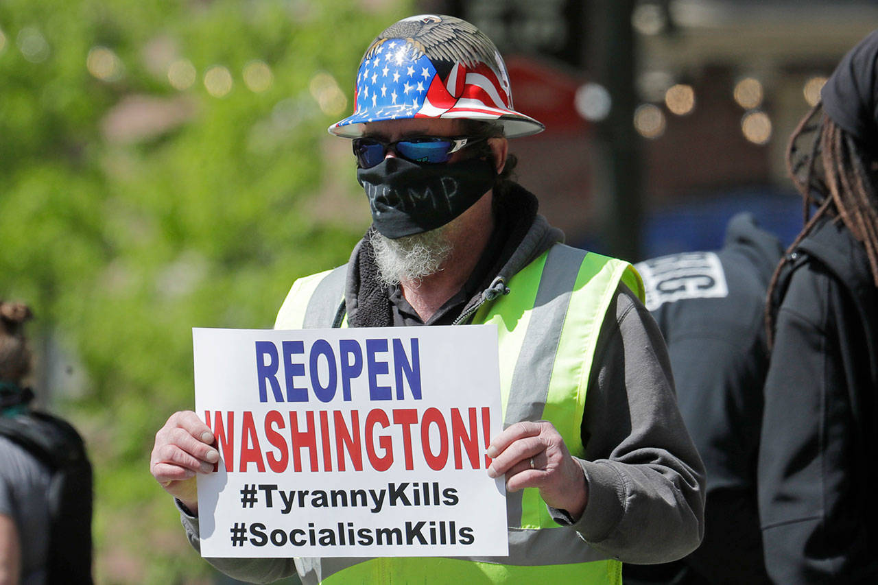A person wears a mask that has “Trump” written on it during a protest against Washington state’s stay-at-home orders, Friday, May 1, 2020, in downtown Seattle. May Day in Seattle traditionally brings large protests and demonstrations from many groups and causes, and this year some people stayed in their cars or otherwise tried to practice social distancing due to the outbreak of the coronavirus. (Ted S. Warren/Associated Press)