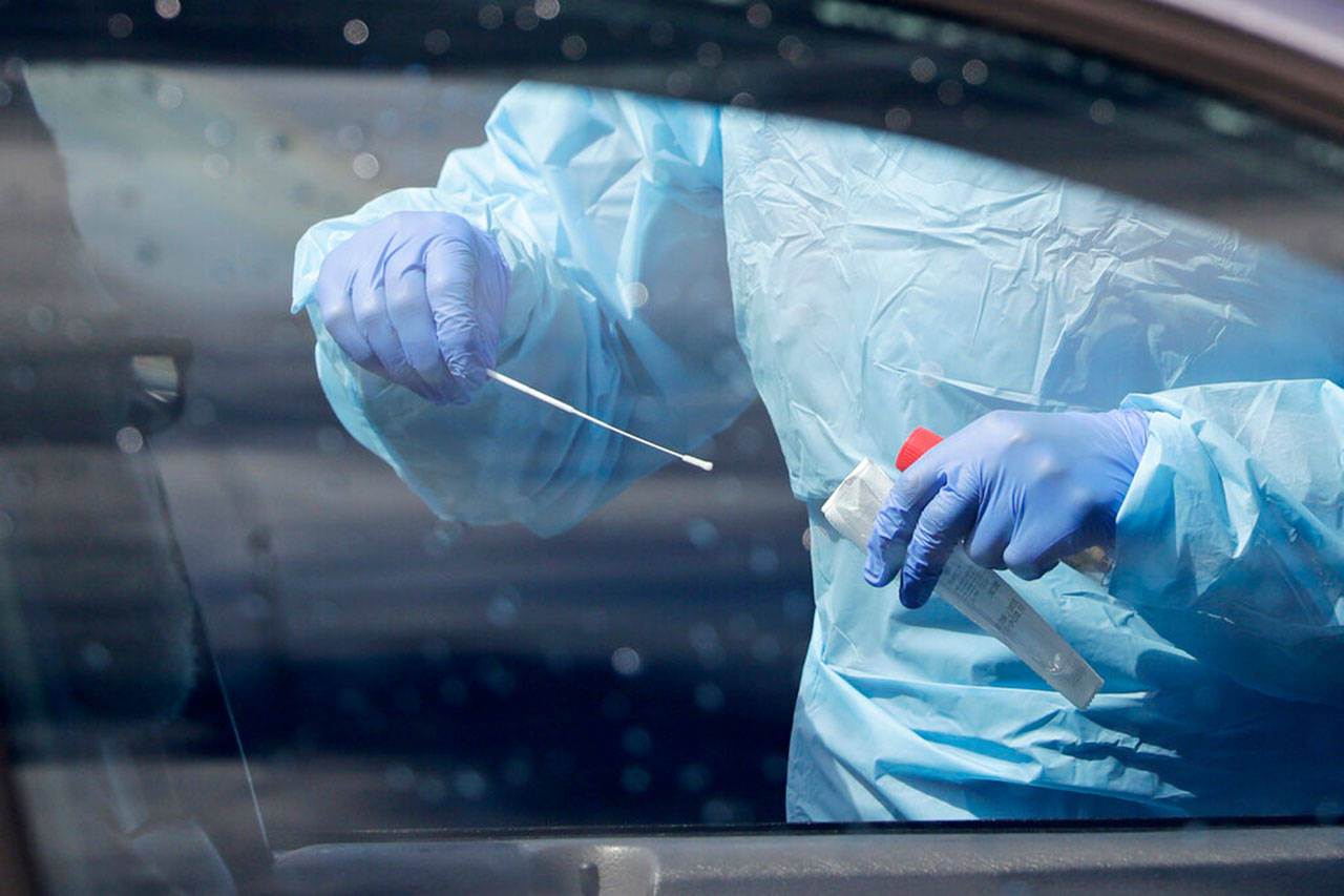 A medical assistant prepares to take a swab from a patient at a new drive-thru and walk-up coronavirus testing site Saturday, April 25, 2020, in Seattle. (Elaine Thompson/Associated Press)