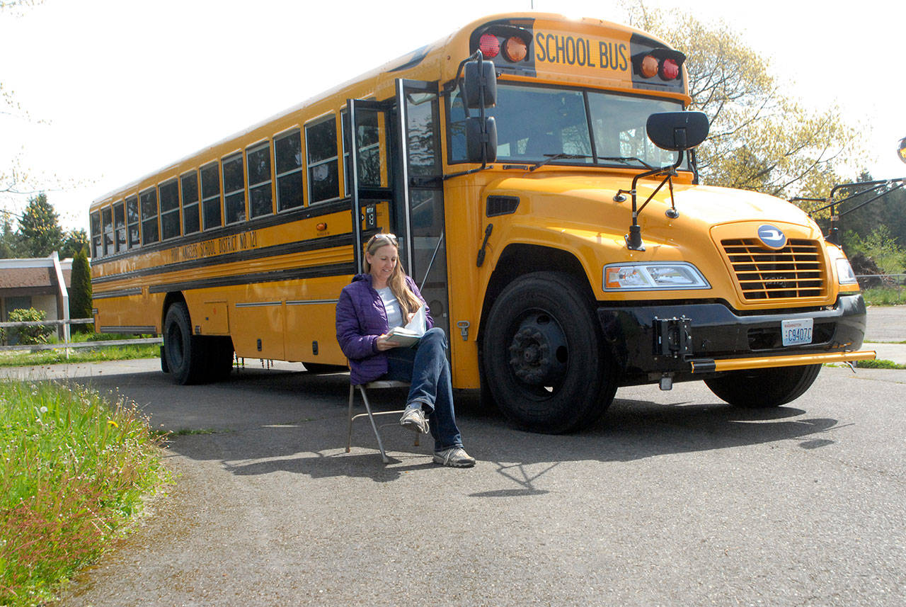 Sue Peterson, a bus driver with the Port Angeles School District, reads while waiting for students at a traveling wifi hot spot on Tuesday in the parking lot of the former Fairview School west of Port Angeles. (Keith Thorpe/Peninsula Daily News)