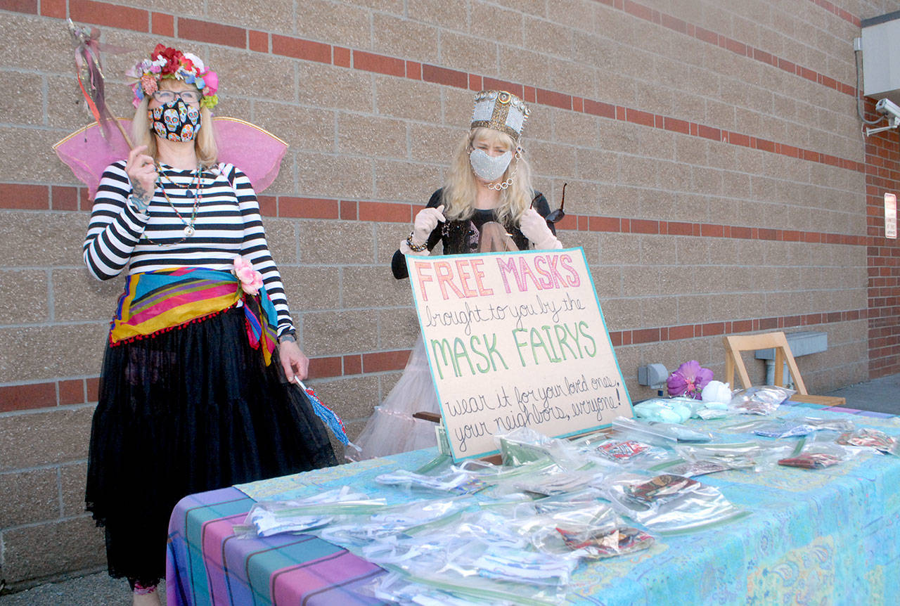 Mask Fairies Jeanette Painter, left, and Barbara Slavik attempt to draw customers of the Lincoln Street Safeway grocery and pharmacy to a table filled with free face masks Tuesday, May 5, 2020, in Port Angeles. (Keith Thorpe/Peninsula Daily News)