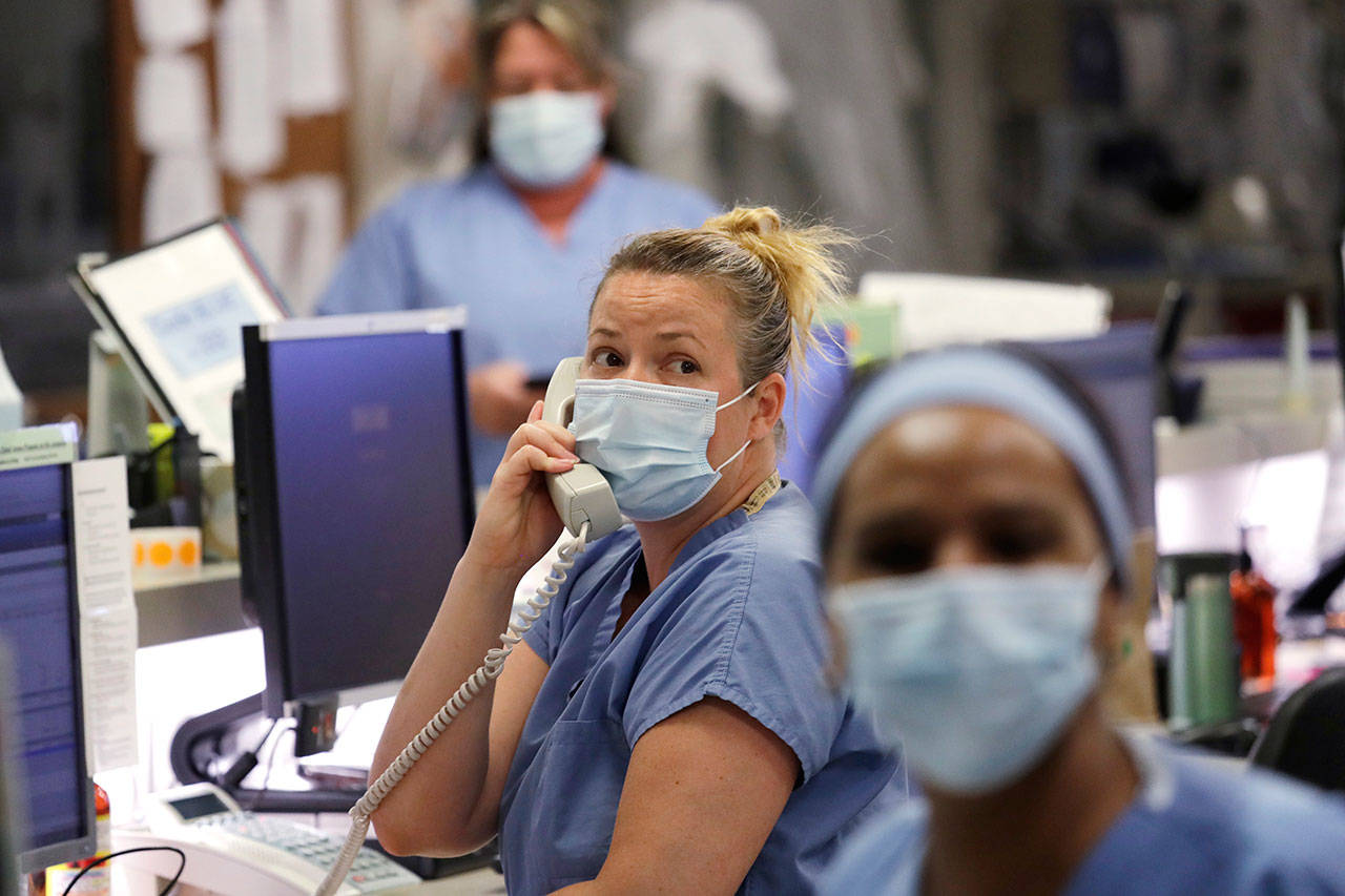 In this May 8 photo, registered nurse Katie Hammond looks up as she talks on the phone in the COVID-19 Intensive Care Unit at Harborview Medical Center, which is part of Seattle-area health care system UW Medicine, in Seattle. UW Medicine, which has played a leading role in responding to the coronavirus outbreak, is now facing a huge financial hole because of the fallout from COVID-19. (Elaine Thompson/Associated Press)