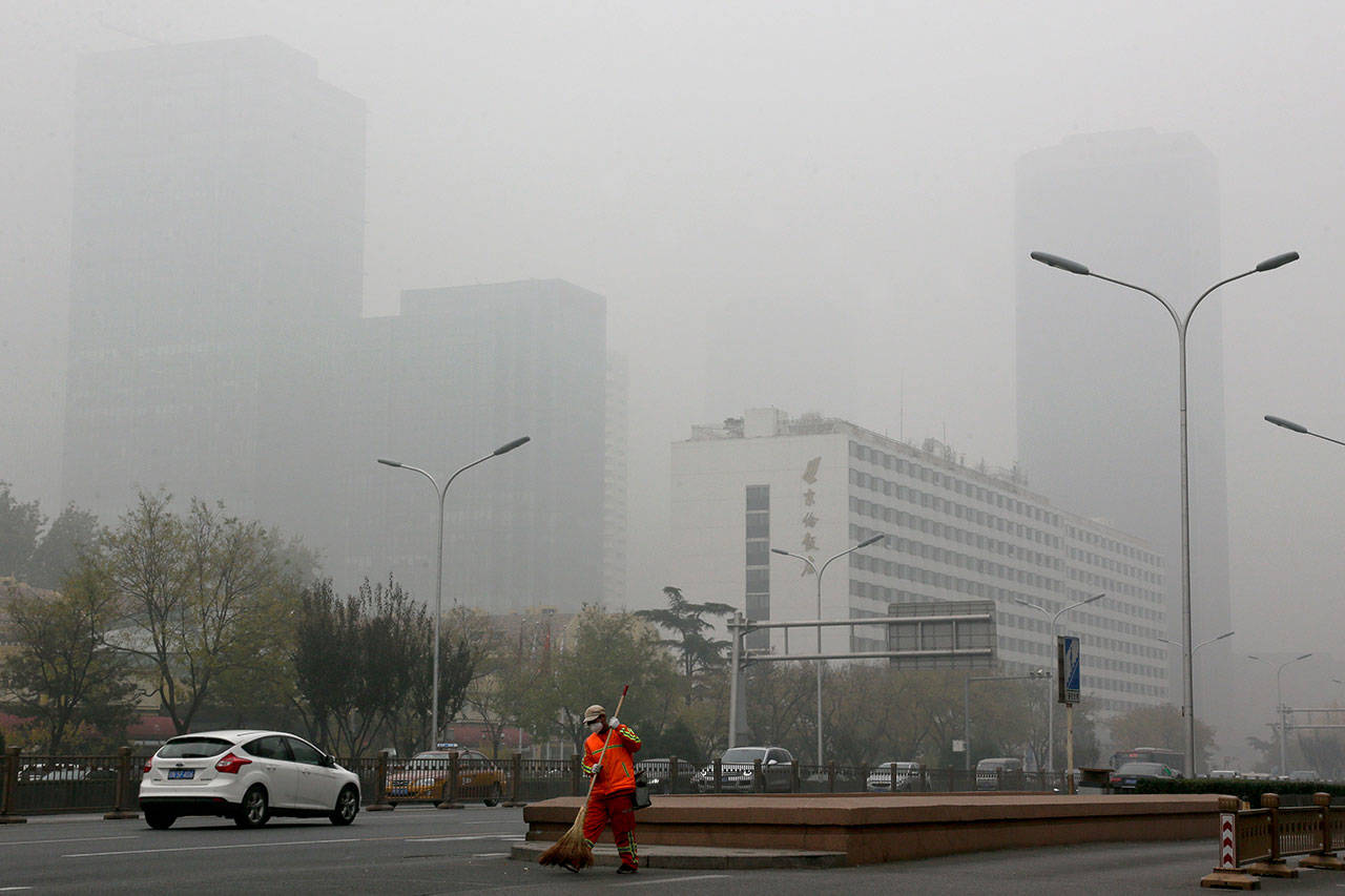 In this Nov. 14, 2018, file photo, a cleaner wearing a mask against pollution sweeps a street in Beijing. The world cut its daily carbon dioxide emissions by 17 percent at the peak of the pandemic shutdown last month, a new study found. But with life and heat-trapping gas levels inching back toward normal, the brief pollution break will likely be “a drop in the ocean” when it comes to climate change, scientists said. (Andy Wong/Associated Press file)