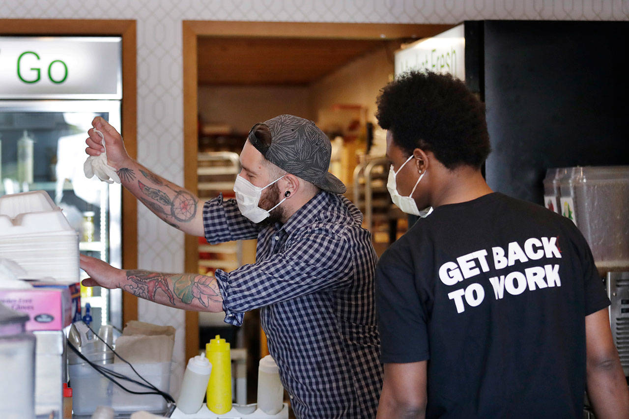 Falafel shop workers Bryant Movern, left, and Javohn Ferguson work to pack customer’s take-out orders in a restaurant otherwise closed because of the coronavirus outbreak Tuesday, May 19, 2020, in Seattle. Washington state Gov. Jay Inslee on Tuesday announced $10 million in grants to small businesses in industries particularly hard-hit by the COVID-19 outbreak. They include restaurants, hair salons, fitness studios and theaters. (Elaine Thompson/Associated Press)