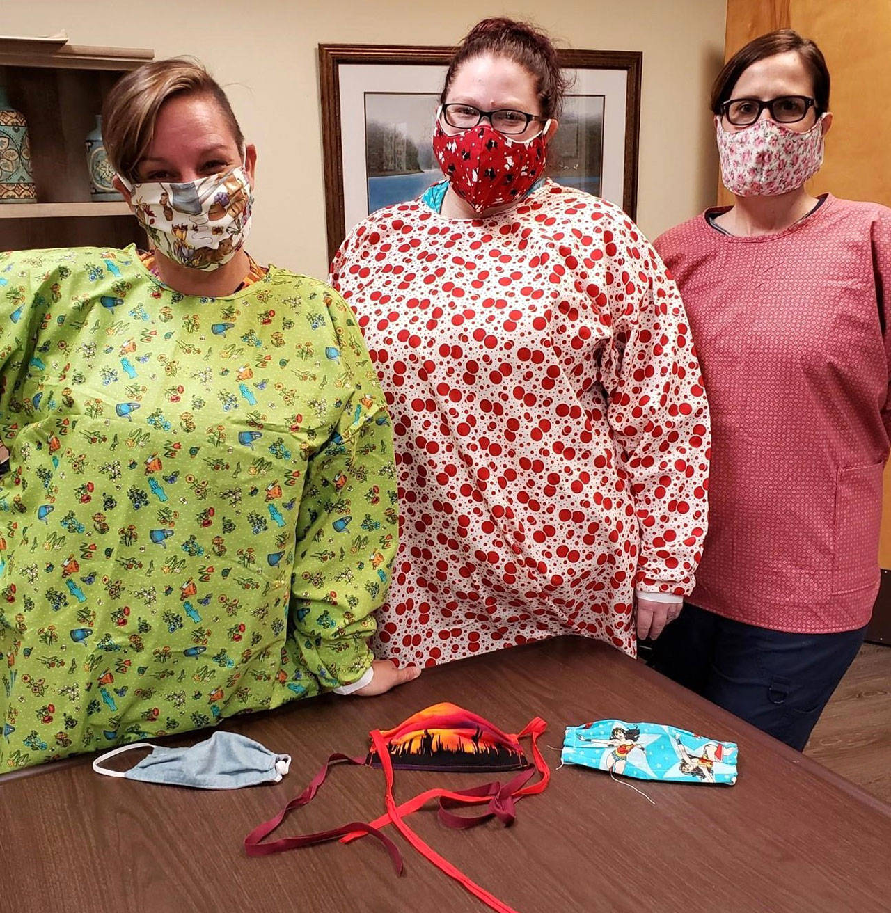 Nurses at Avamere Olympic Rehabilitation of Sequim, from left, Lynda Lyons, CNA; A.J. Henning, CNA; and Jo Talbot, RN; show masks and gowns made by members of Sunbonnet Sue Quilt Club. In total, club members made more than 4,500 face masks for community health workers. (Photo courtesy of Avamere/Sunbonnet Sue Quilt Club)