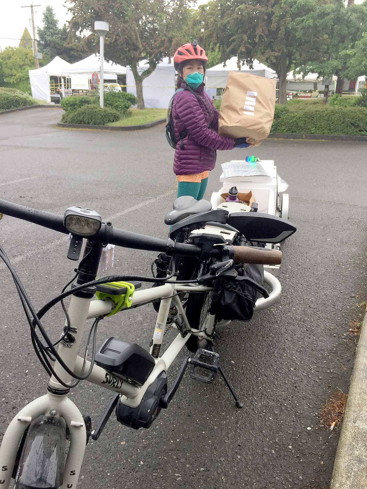 Judi Jennings loads her bike up on Saturday at the Port Townsend Farmers Market with groceries to deliver to a Port Townsend resident as part of the new bike delivery service for online market customers. (Amanda Milholland)