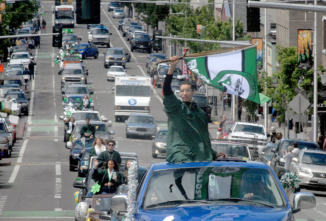 Graduating senior Damen Ringgold waves a Roughrider flag as he takes part in a graduation procession for Port Angeles High School through the streets of Port Angeles on Friday. (Keith Thorpe/Peninsula Daily News)