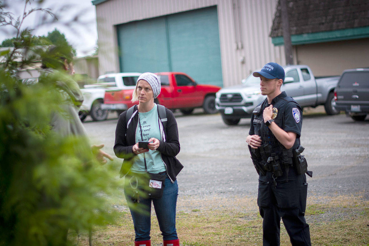Rediscovery Program Director Amy Miller and Port Angeles Police Officer Jackson Vandusen talk with a man experiencing homelessness who was reported for trespassing. (Jesse Major/for Peninsula Daily News)