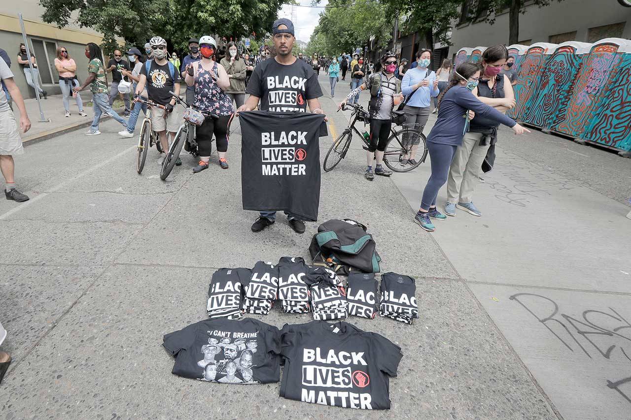 A man sells Black Lives Matter T-shirts Sunday inside what has been named the Capitol Hill Occupied Protest (CHOP) zone in Seattle. Protesters calling for police reform and other demands have taken over several blocks near downtown Seattle after officers withdrew from a police station in the area following violent confrontations. The CHOP name is a change from CHAZ (Capitol Hill Autonomous Zone) that was used earlier in the week. (Ted S. Warren/Associated Press)
